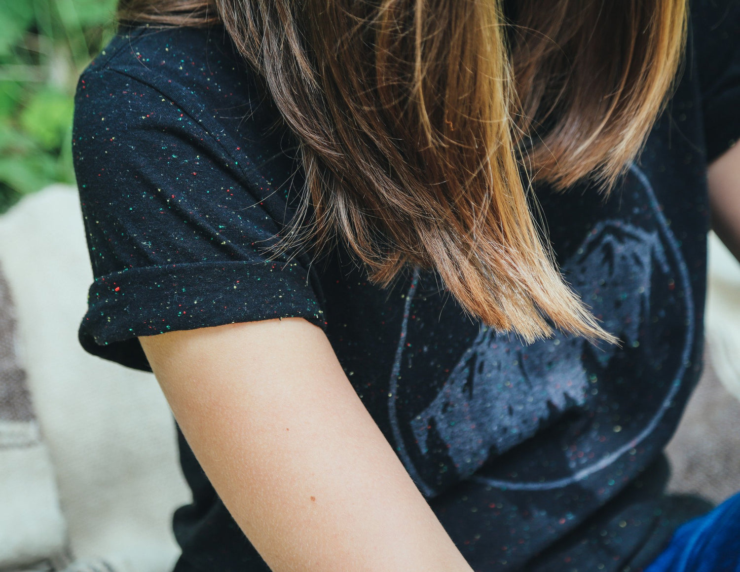 Close up of woman wearing black with white speckle tee shirt featuring moonrise over mountain range graphic.