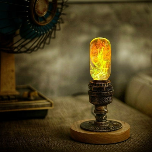 Oval decorative resin bulb with orange and yellow flame like streaks inside, sits lit atop vintage brass pipe and wood base.