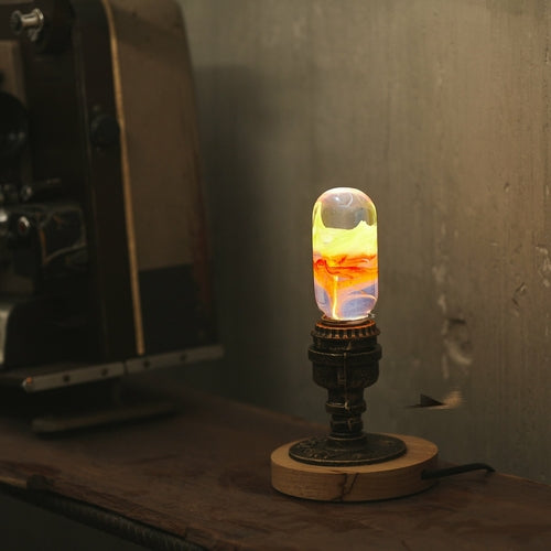 Oval decorative resin bulb with orange and yellow and red horizontal streaks inside, sits lit on vintage brass and wood base.