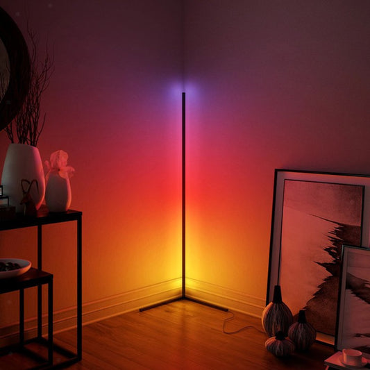 Minimalist Corner RGB floor lamp, lit with purple, red and orange and yellow light casting color into corner of a room.