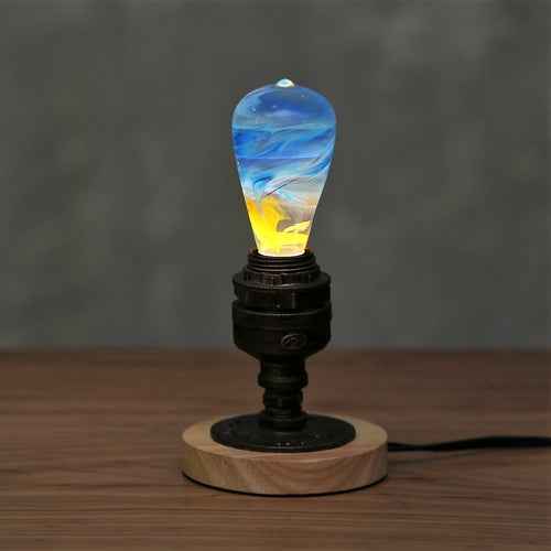 Illuminated clear lightbulb, filled with yellow, orange, red, and blue swirls, set in vintage copper and wood base atop wood.