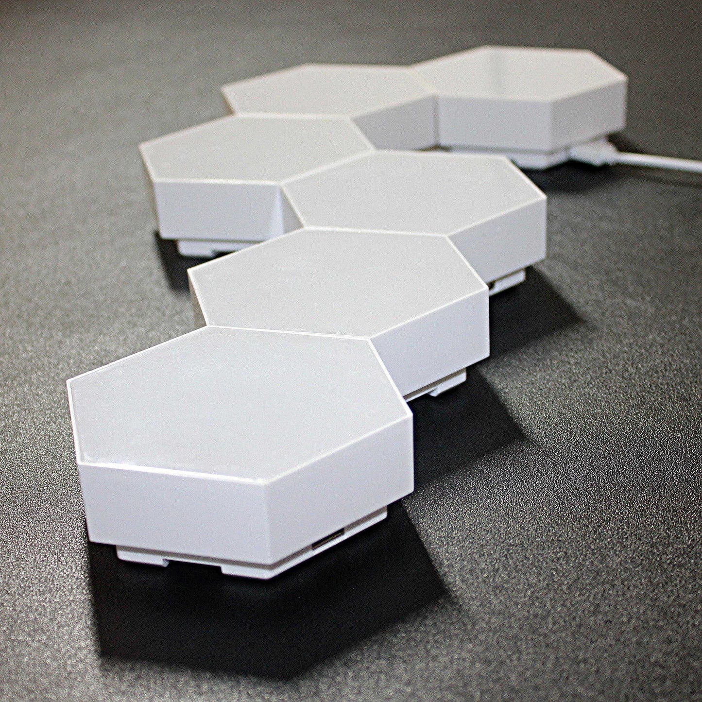 All 6 Touch Sensitive Honeycomb Modular Wall Lights shown connected but unlit, on a table top from the side to show depth. 