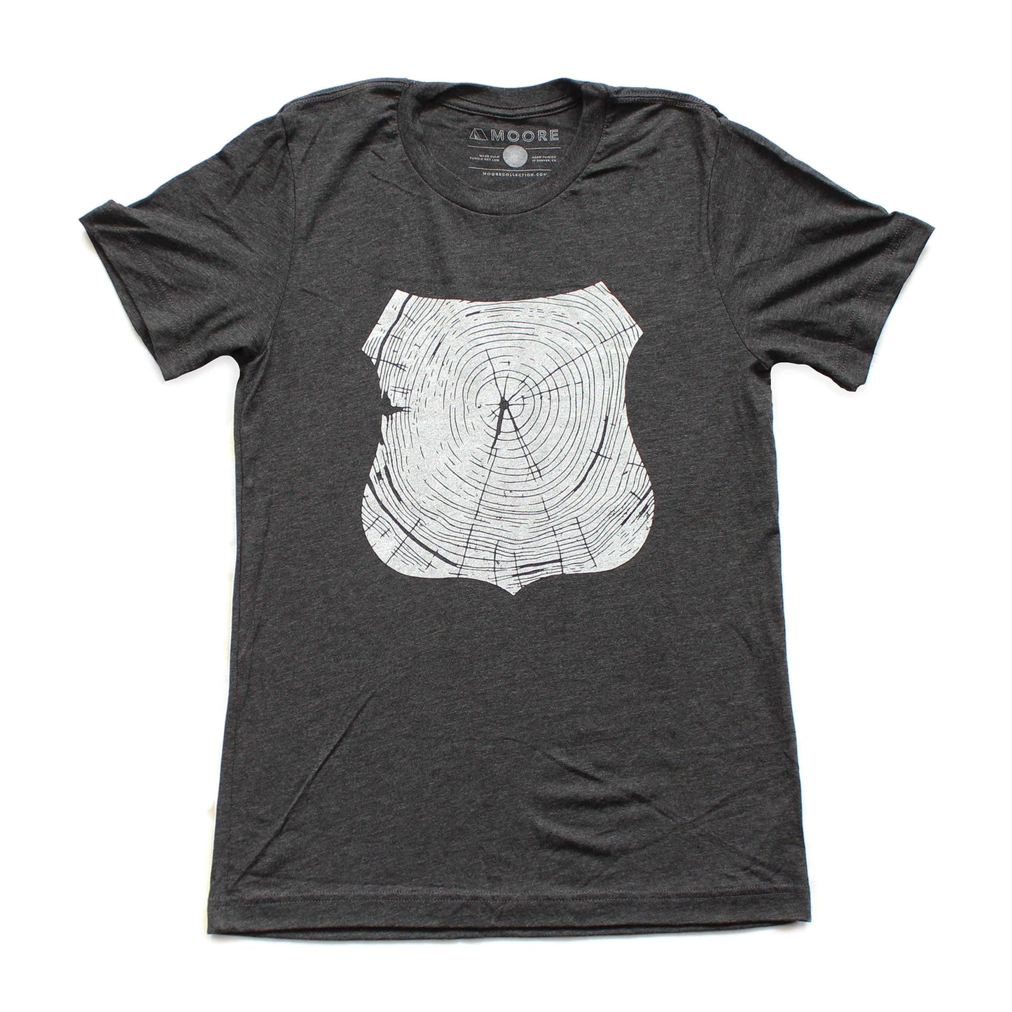 Gray short sleeved tee shirt printed with white forest ranger badge outline, filled with tree rings, laid out flat.