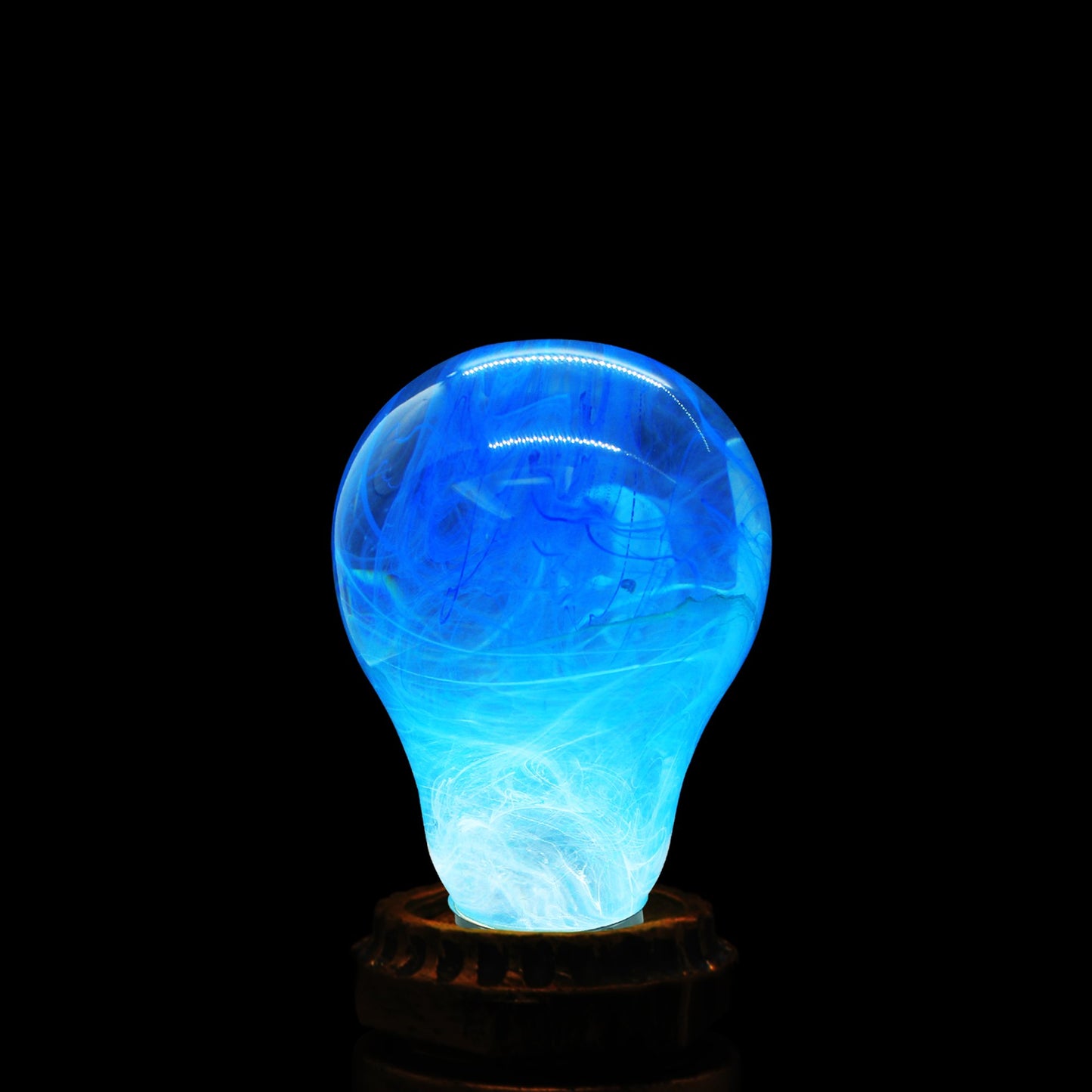 Illuminated clear lightbulb filled with white and blue swirls set in vintage copper colored base.