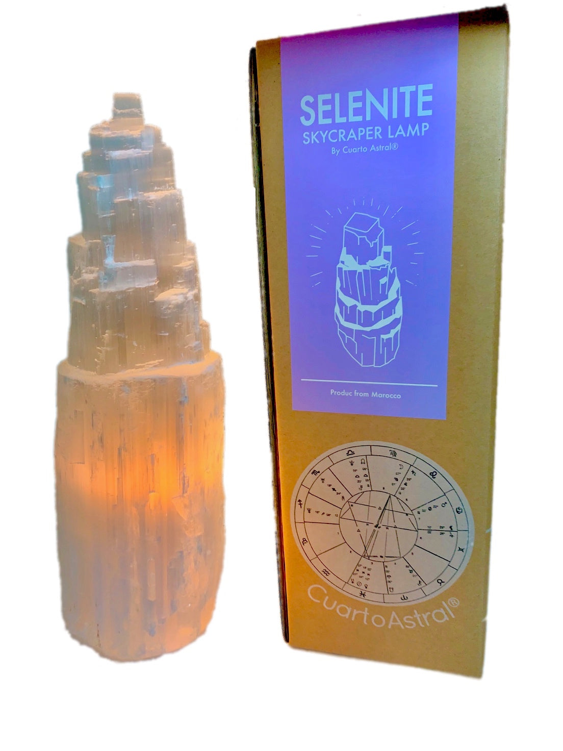 Selenite skyscraper lamp, glowing from light within, beside with cardboard packing box from which it came.