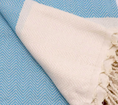 	Blue and white chevron patterned Turkish hand towel with diagonal fold showing tassels.