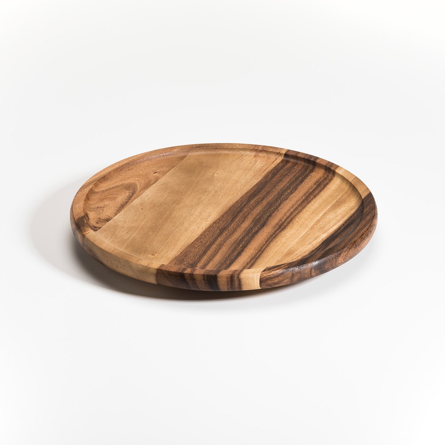 Rotating circular lazy susan made of acacia wood with prominent grain on white background.