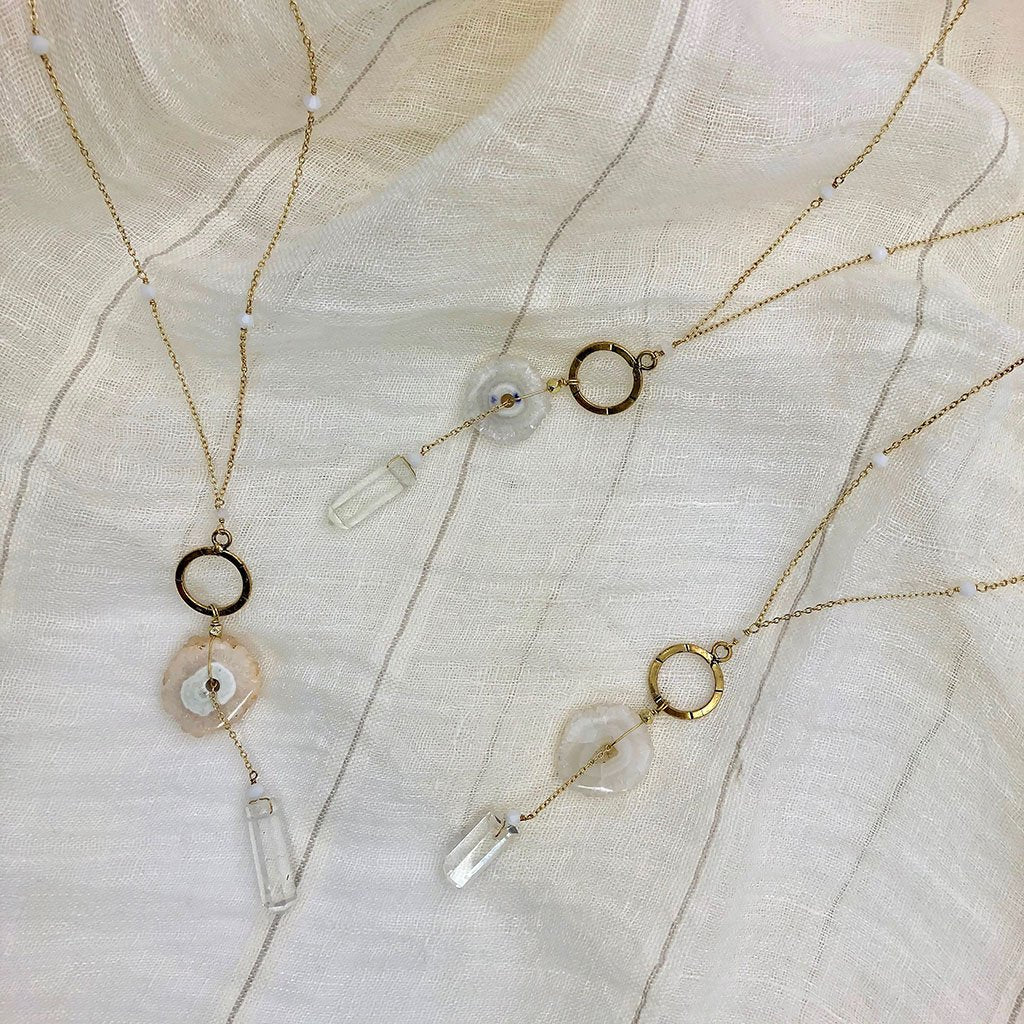 Three solar quartz necklaces shown on a cloth background, accenting natural differences in the stones.